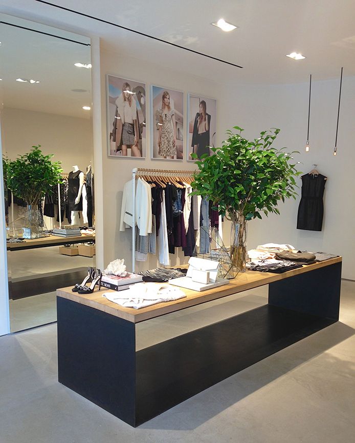 a clothing store with clothes on display and plants in vases next to the counter