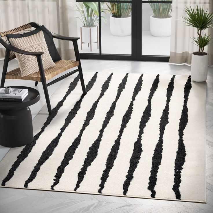 a black and white striped rug in a living room with a chair, window, and potted plant