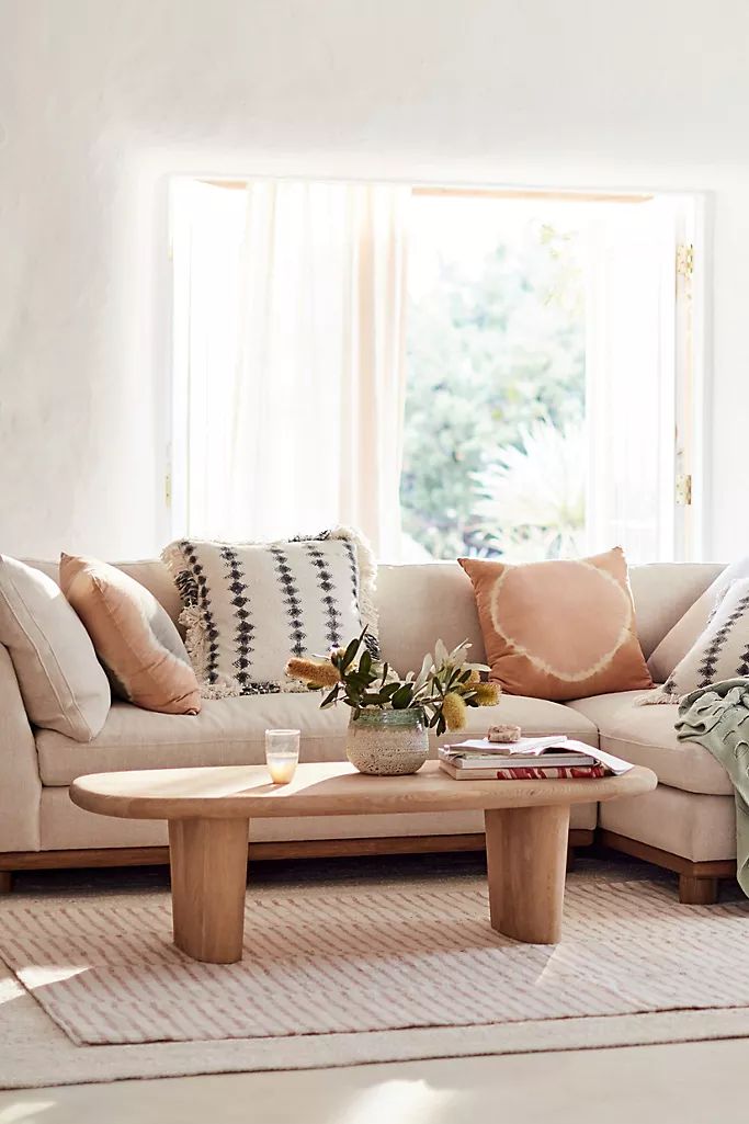 a living room filled with furniture and pillows on top of a rug in front of a window