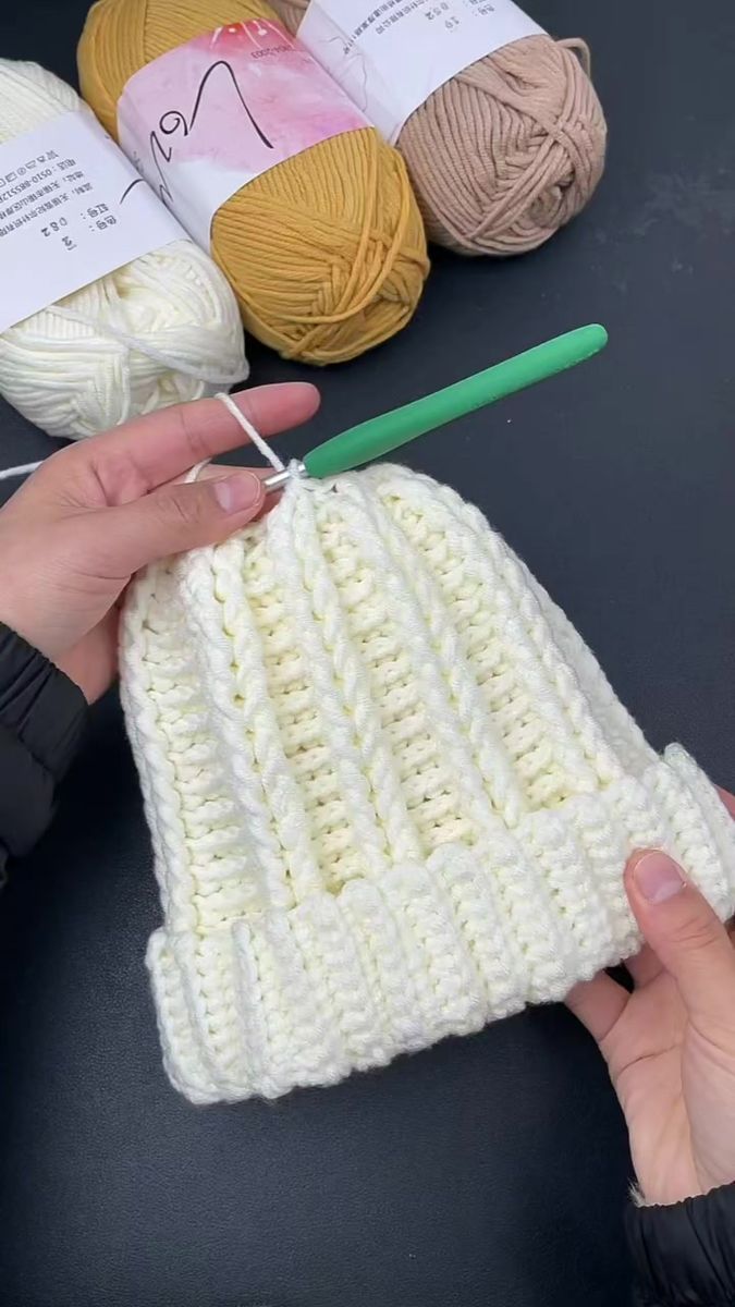 someone is knitting yarn on top of a crochet bag with two skeins next to it