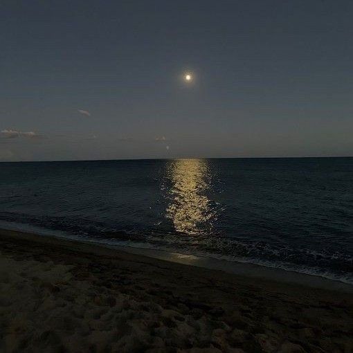 the moon is shining over the ocean on a clear night with no one in sight