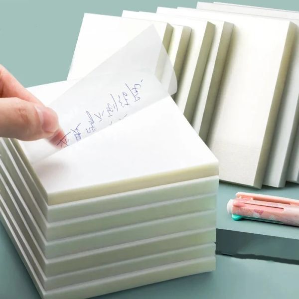 a hand holding a piece of paper next to several stacks of post - it notes