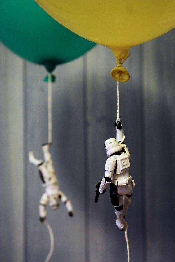 two small toy figures hanging from strings next to each other in front of a balloon