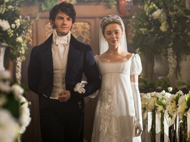 a young man and woman dressed in period clothing standing next to each other at a wedding ceremony