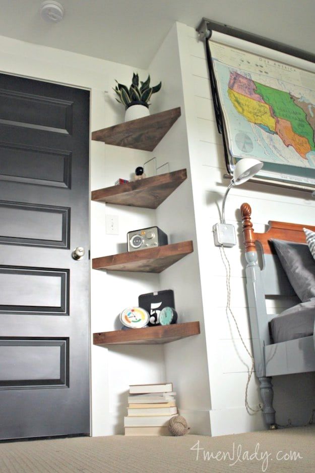 a bed room with a neatly made bed and bookshelves on the wall above it