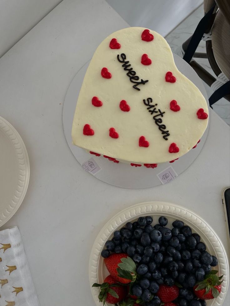 a cake with red, white and blue hearts on it sitting next to a bowl of strawberries