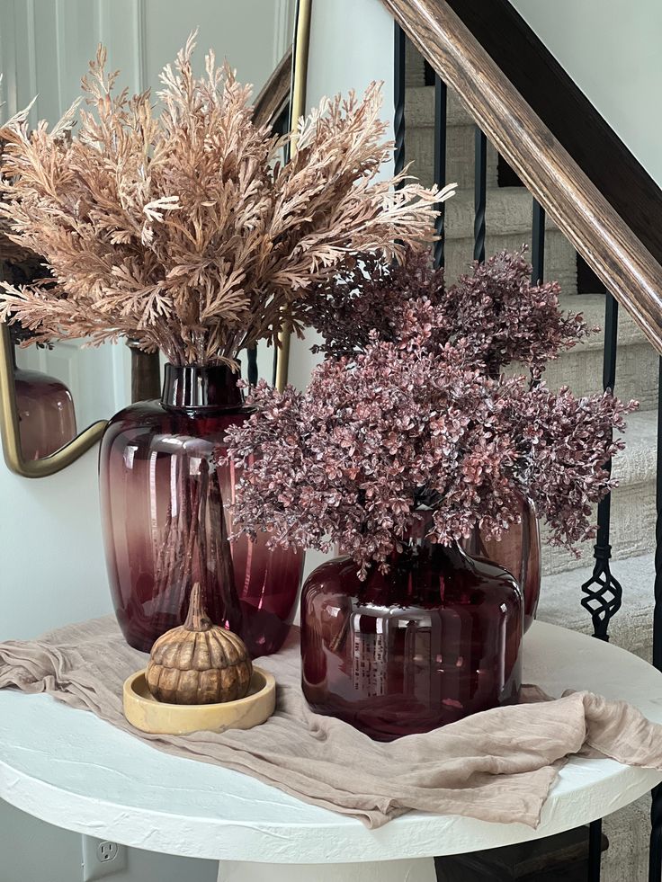 three vases filled with flowers sitting on top of a table next to a stair case