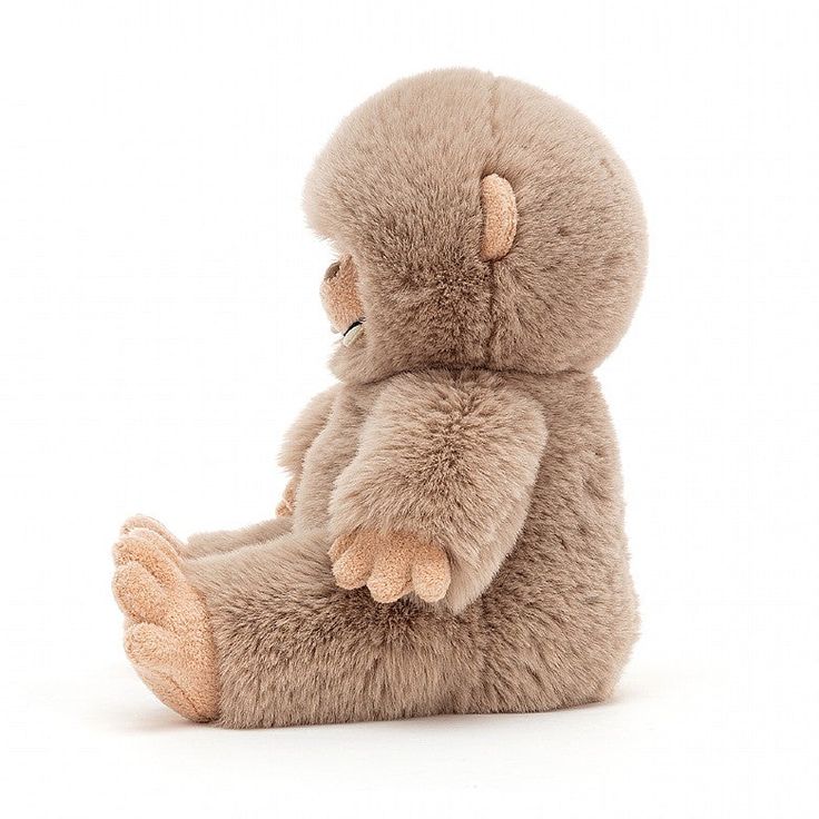 a stuffed animal sitting on the ground with its legs crossed and eyes closed, in front of a white background