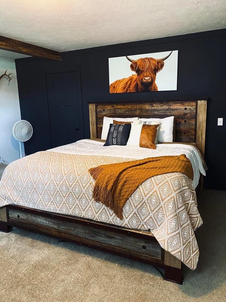 a bedroom with a large bed and cow painting on the wall