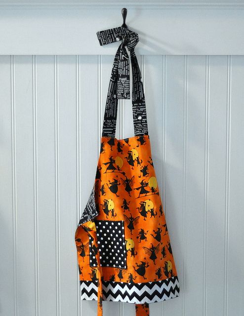 an orange apron hanging on the wall with black and white patterns, halloween pumpkins