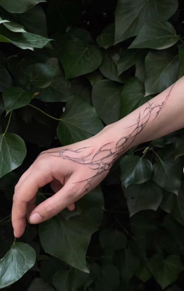 a person's arm with vines on it and a hand holding something in front of them