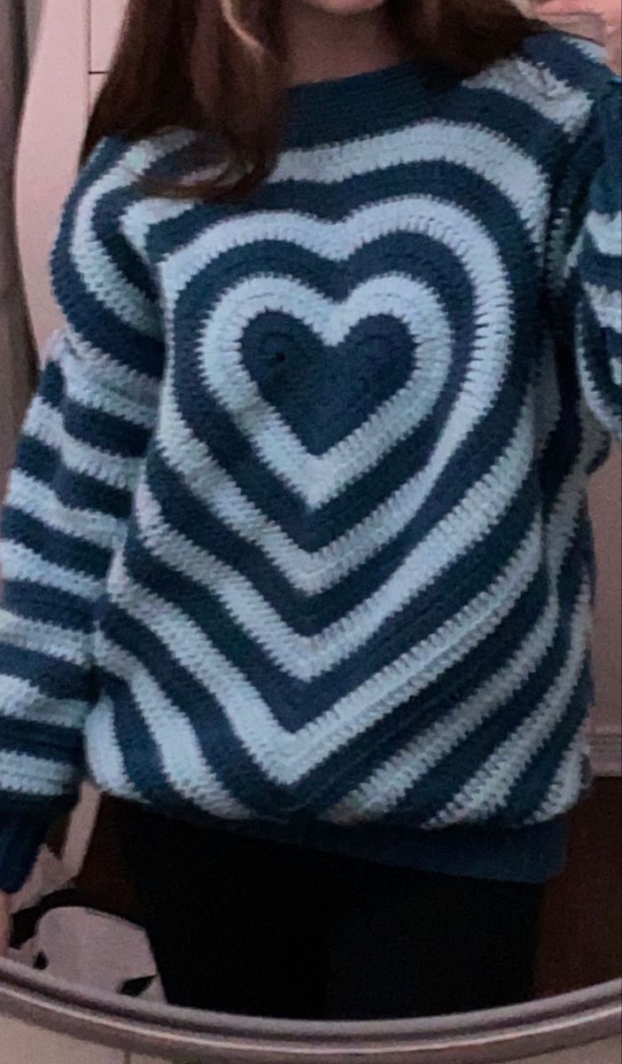 a woman standing in front of a mirror wearing a sweater with a heart on it