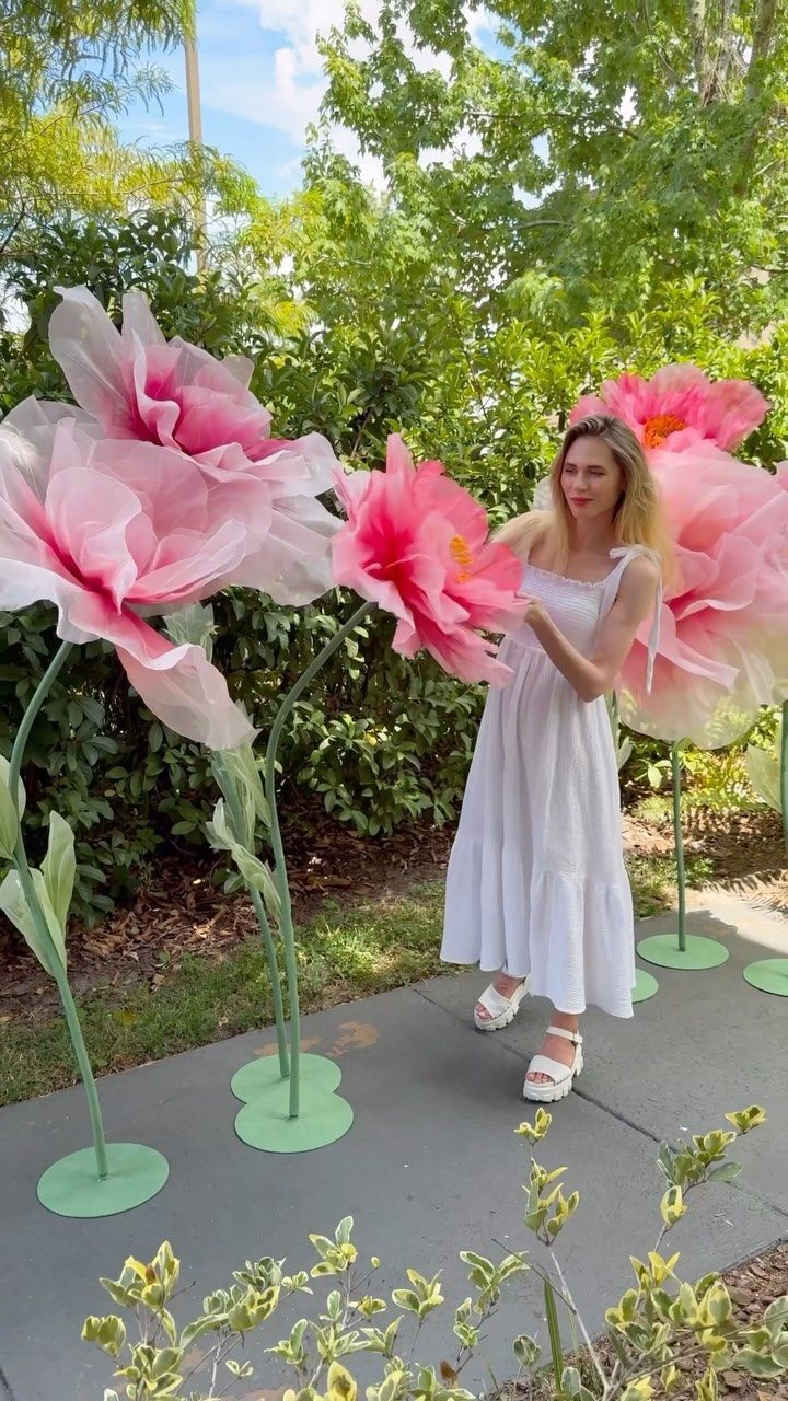 a woman in white dress holding large pink flowers