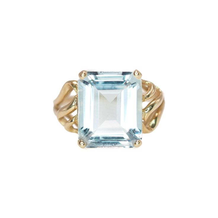 "Simple and elegant, this gorgeous pale blue 5.11-carat aquamarine is set into 14K yellow gold. The glistening gold wirework pops against the sparkly aquamarine. Crafted in the 1980s, the emerald-cut gemstone delivers excellent light return, making the ring glow. A perfect gift for a March baby! The name aquamarine means \"seawater\" in Latin and is thought to contain the spirit of the ocean. Ancient sailors thought that wearing aquamarine would calm stormy seas. Aquamarine is a member of the be Classic Light Blue Emerald Cut Jewelry, Classic Light Blue Aquamarine Jewelry, Emerald Cut Aquamarine Gold Jewelry, Elegant Yellow Gold Ring With Aquamarine, Formal Aquamarine Solitaire Jewelry, Fine Jewelry In 14k Gold With Light Blue Color, Light Blue 14k Gold Fine Jewelry, Elegant Light Blue 14k Gold Jewelry, Classic Light Blue Jewelry For Formal Occasions