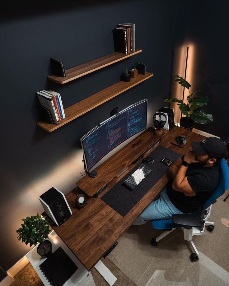 a person sitting at a desk with a computer on it and bookshelves above