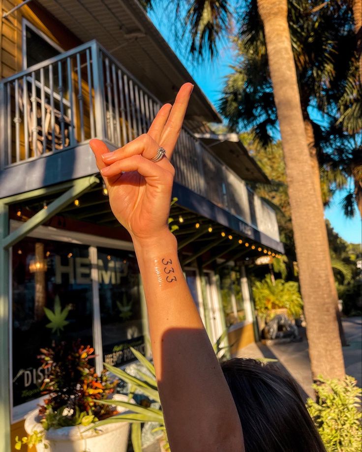 a woman is holding up her peace sign in front of a building with palm trees