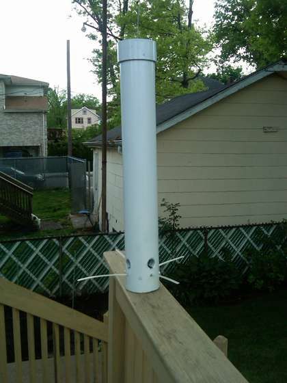 a white pole sitting on the side of a wooden fence next to a house and yard