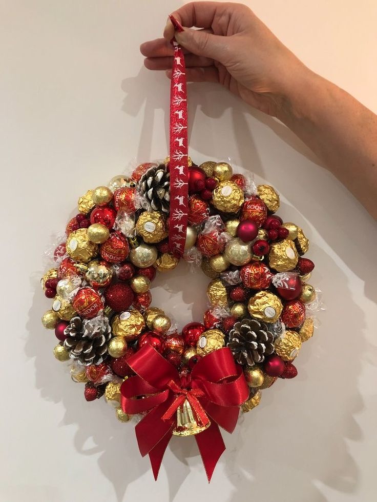 a hand holding a christmas wreath with chocolates on it