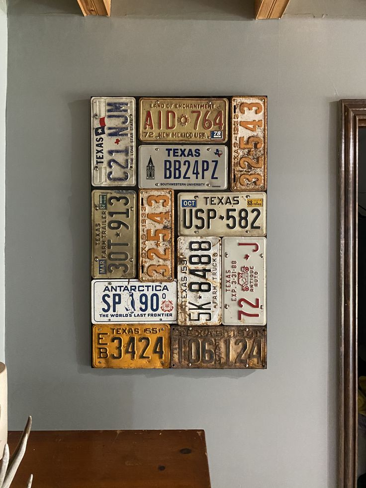 an old license plate wall hanging on the wall in a room with a wooden table and mirror