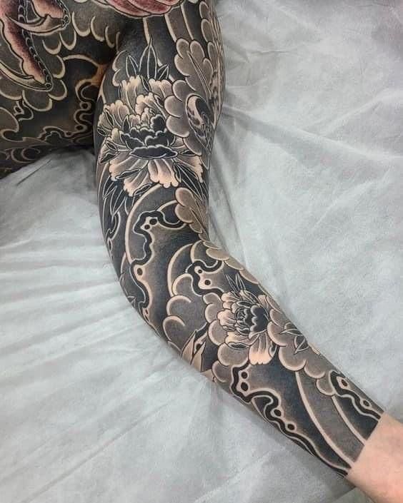 a person laying on top of a bed with tattoos on their arms and legs