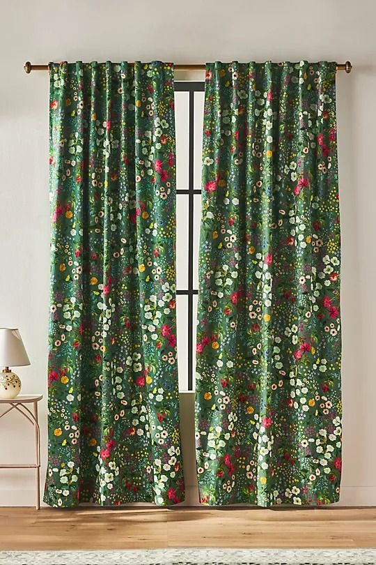 a green floral curtain hanging on the side of a window