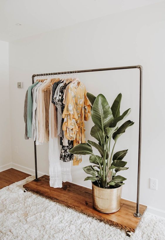 a potted plant sitting on top of a wooden shelf next to a clothes rack