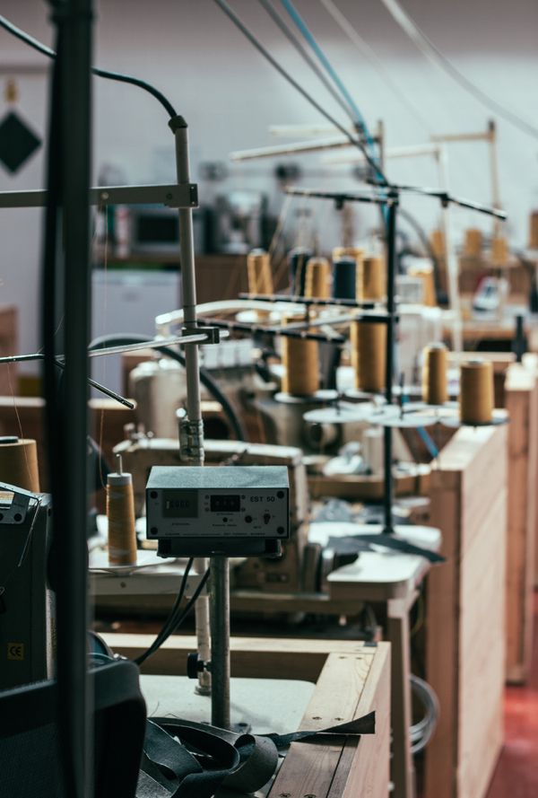 many sewing machines are lined up in the room with lots of thread spools