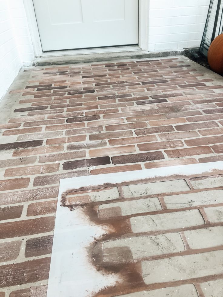 a brick floor with white paint and pumpkins on the ground in front of it