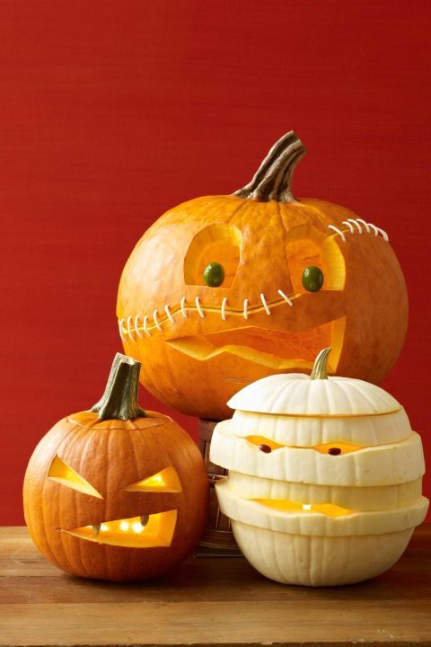 three carved pumpkins sitting on top of a wooden table with their faces cut out