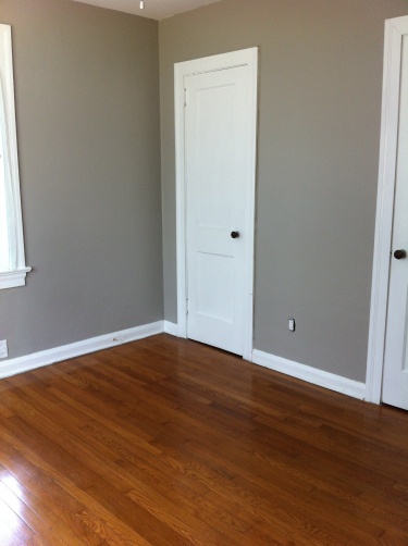 an empty room with hard wood floors and white doors on the door way to another room