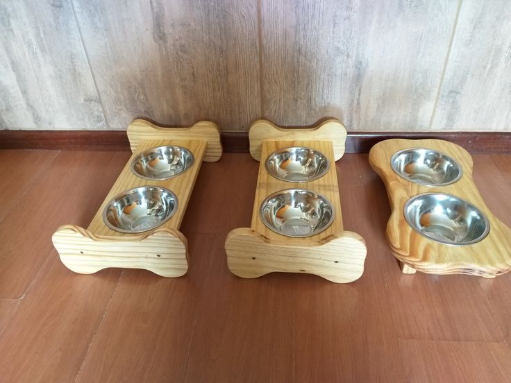 three wooden bowls with metal dishes in them on a wood floor next to a wall