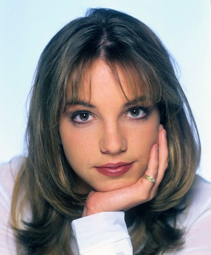 a close up of a person wearing a white shirt with her hand on her chin