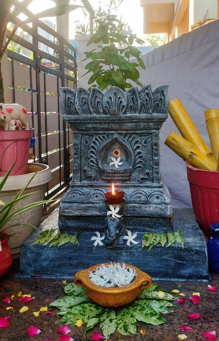 a small fountain with some food in it and flowers on the ground next to it