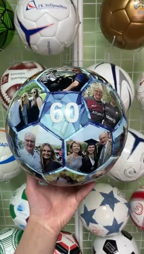 a person holding up a soccer ball with photos on it