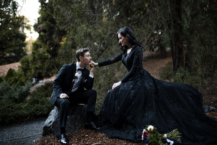 a man kneeling down next to a woman in a black dress