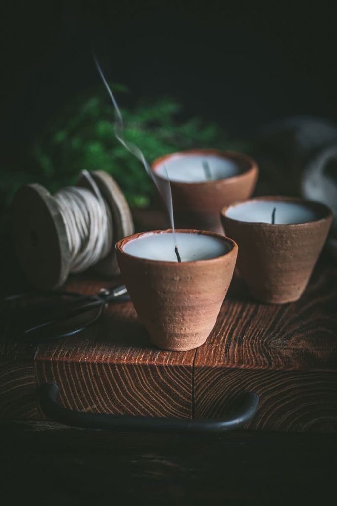 three clay bowls with candles sitting on top of a wooden table next to twine of yarn