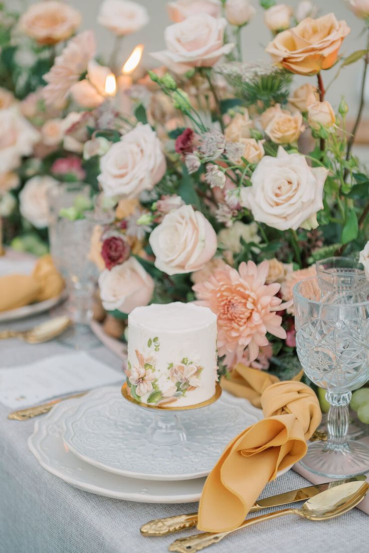 a table topped with a white cake and lots of flowers