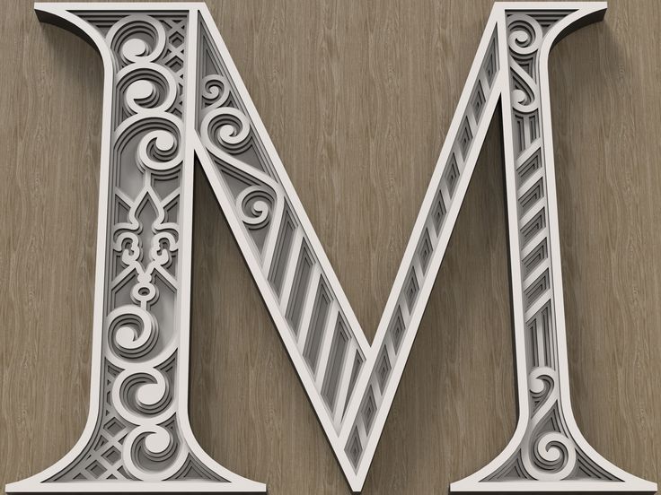 the letter m is made up of white paper with swirly designs on it's sides