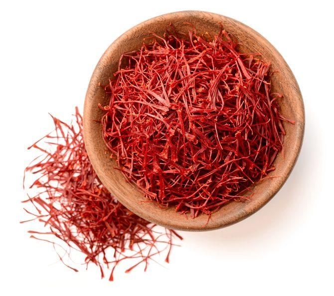 a wooden bowl filled with red cranberries on top of a white table