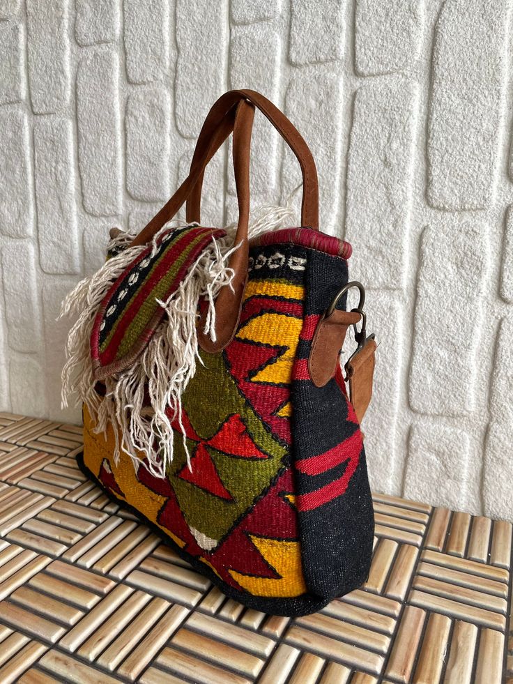 Add a unique piece to your winter outfit style with a bohemian carry-all large tote with yarn tassels colored with natural root dyes in a hand-woven traditional wool rug. Handle and upper part are made of genuine leather. You can remove the strap according to your daily style. You can use this purse as a shoulder bag or handbag. Shoulder strap is adjustable. Suitable for using as a crossbody bag. Together with the bag, we will send two straps, one in real leather and one in guitar strap. You can use these straps by changing them according to your clothing style. You can personalize this unique yellow bag by adding a name to it and make an unforgettable surprise for your loved ones. It is a meaningful gift for bohemian style lovers. It is an ideal choice as a birthday gift to sister, gradua Bohemian Yellow Woven Shoulder Bag, Yellow Bohemian Handwoven Shoulder Bag, Bohemian Multicolor Handwoven Shoulder Bag, Bohemian Shoulder Bag For On-the-go With Large Capacity, Bohemian Multicolor Handwoven Satchel, Wool Tote, Rug Bag, Personalized Valentines, Guitar Strap