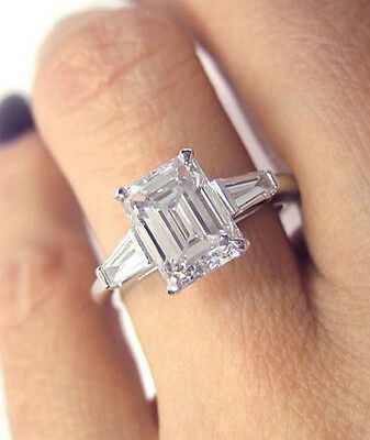 a woman's engagement ring with an emerald and baguette cut diamond