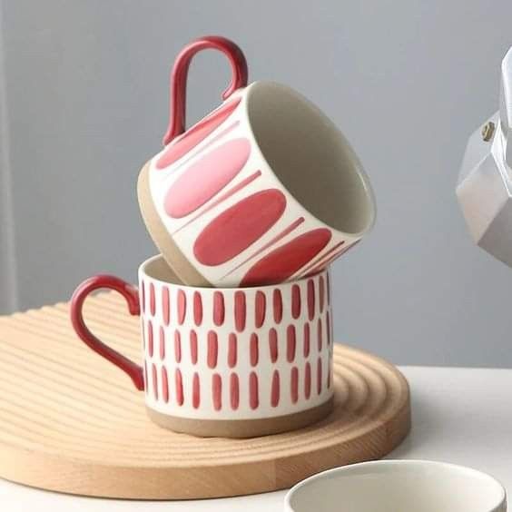 two coffee cups sitting on top of each other next to a cup holder and saucer