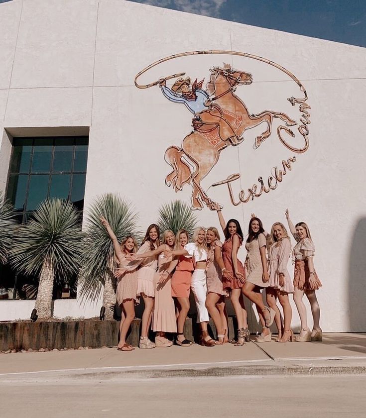 a group of women standing in front of a building with a horse painted on it