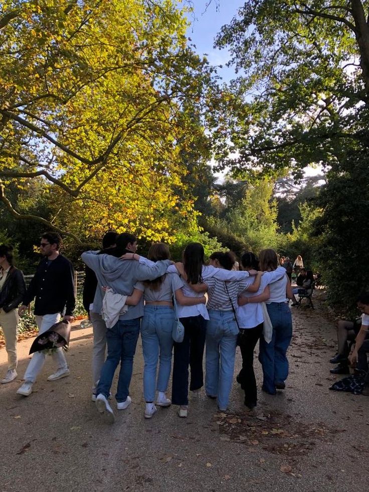 a group of people hugging each other in the middle of a path surrounded by trees