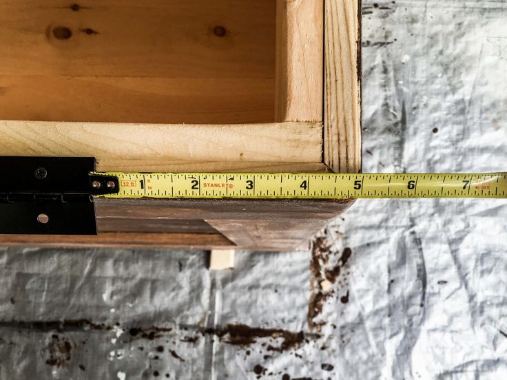 a wooden shelf with a measuring tape on it and a piece of wood in the background