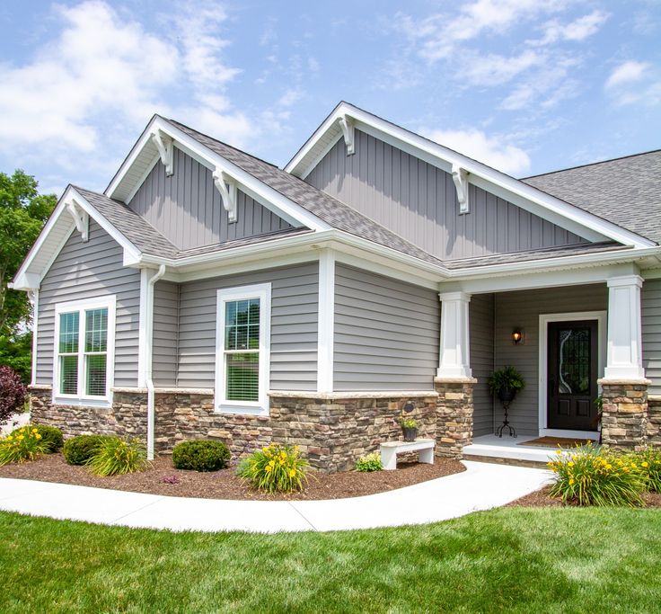 a gray house with white trim on the front door and windows, grass in front