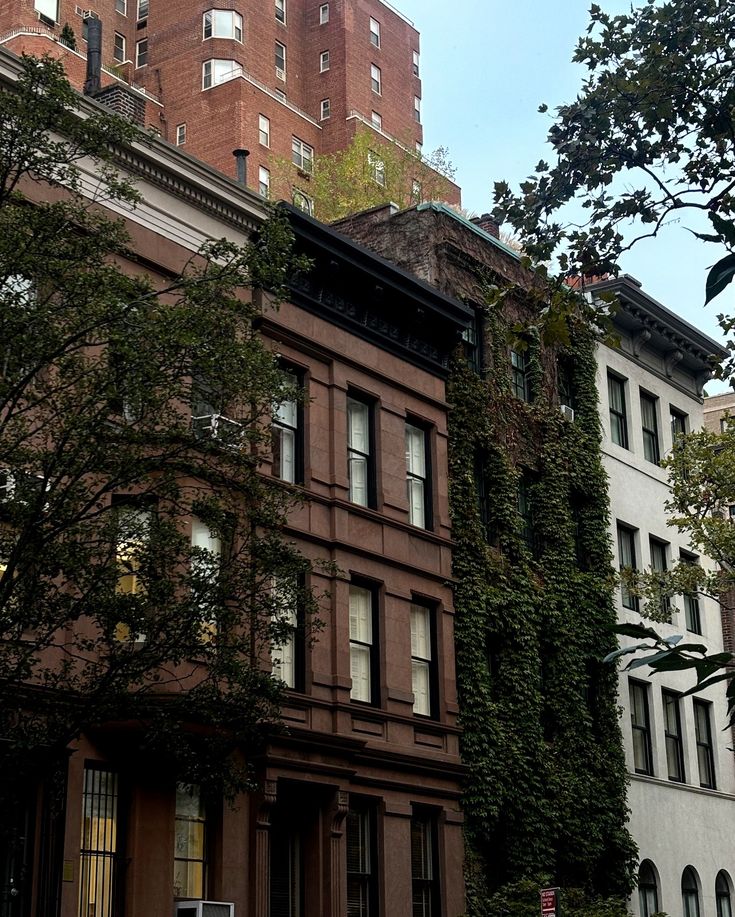 an old building with ivy growing on it's side in front of tall buildings