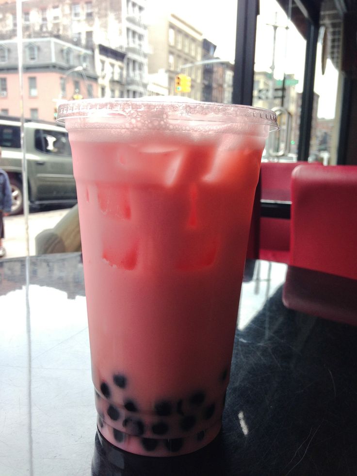 a pink drink sitting on top of a table next to a glass window filled with liquid