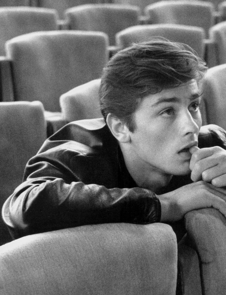 black and white photograph of a man sitting in an empty auditorium with his hand on his chin