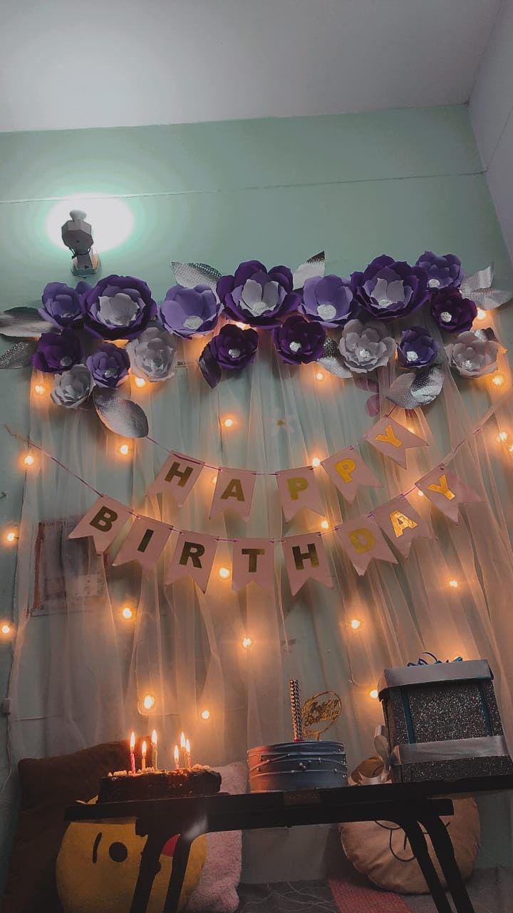 a birthday party with purple and silver decorations on the wall next to a table filled with candles